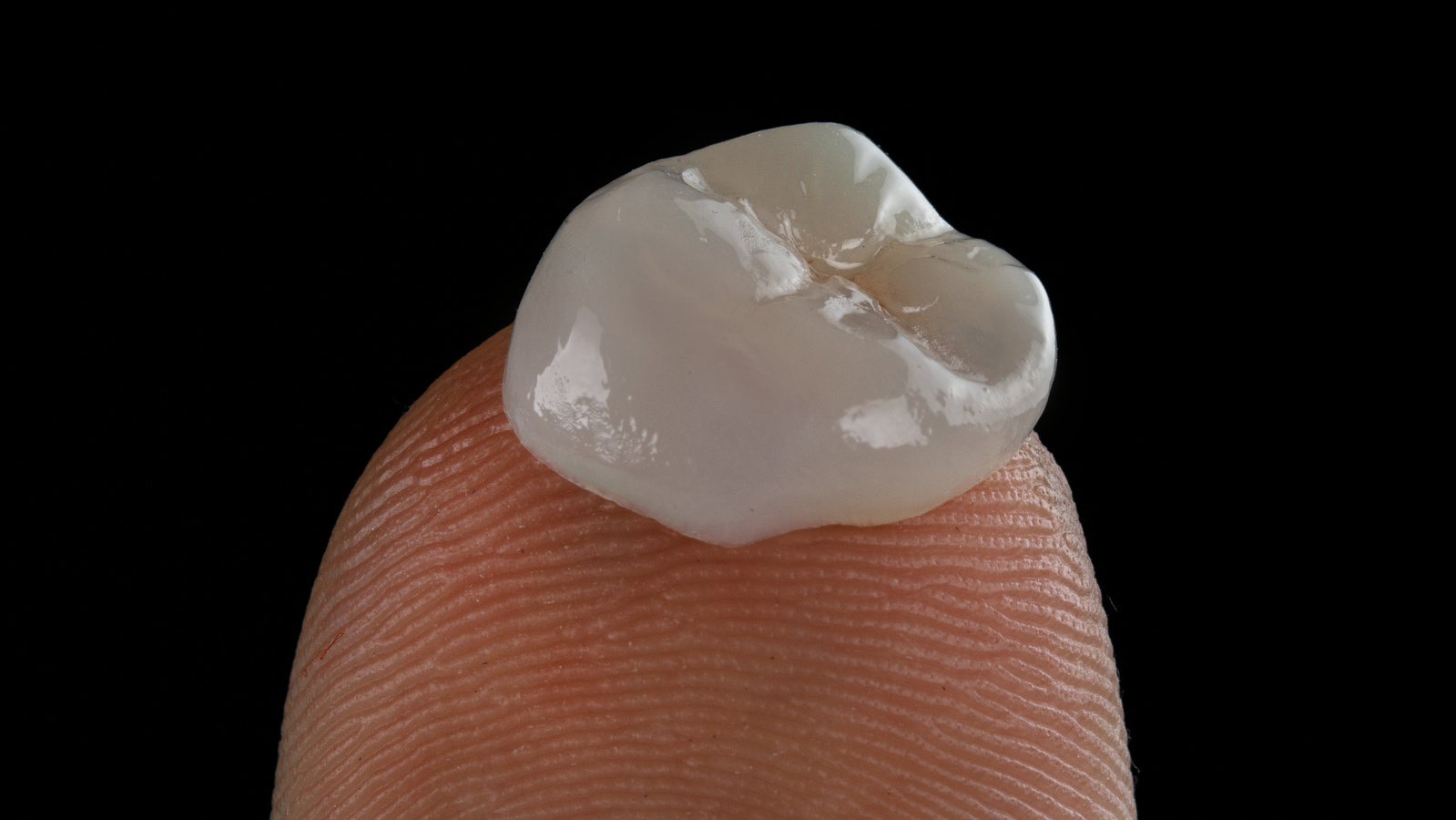 Ceramic crown for chewing tooth on a finger with texture on